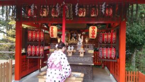 Jeune fille en kimono devant un petit autel shintoïste